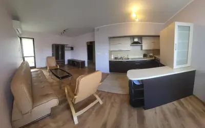a living room with a table and chairs and a kitchen at Apartament Lea in Kraków