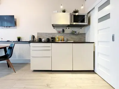 a kitchen with white cabinets and a microwave at Batorego loft - 5 minutes to Main Square in Kraków
