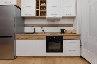 a kitchen with white cabinets and a sink and a refrigerator at One-Bedroom Kazimierz Apartment for Home Office Starowiślna by Noclegi Renters in Kraków