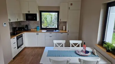 a kitchen with white cabinets and a table and chairs at Sun & Garden View in Oświęcim