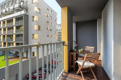 a balcony with a table and a chair and a building at Apartament z 2 Sypialniami Kraków Parking Blisko Tauron Arena by Noclegi Renters in Kraków