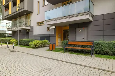 a bench sitting in front of a building at Apartament z 2 Sypialniami Kraków Parking Blisko Tauron Arena by Noclegi Renters in Kraków