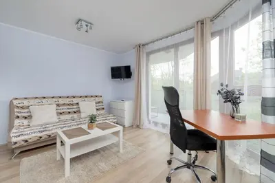 a white living room with a desk and a table at Studio z Parkingiem i Balkonem w Krakowie by Rent like home in Kraków