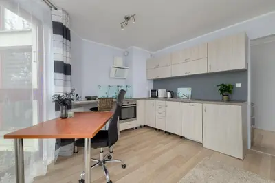a kitchen with white cabinets and a wooden table at Studio z Parkingiem i Balkonem w Krakowie by Rent like home in Kraków