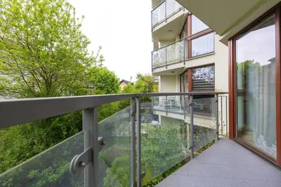 a balcony with glass railing and a view of a building at Studio z Parkingiem i Balkonem w Krakowie by Rent like home in Kraków