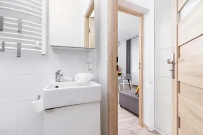a white bathroom with a sink and a mirror at Apartment Bosacka Cracow by Noclegi Renters in Kraków