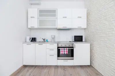 a kitchen with white cabinets and a brick wall at Apartment Bosacka Cracow by Noclegi Renters in Kraków
