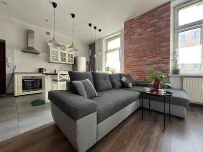 a living room with a couch and a brick wall at Traugutta 24 Przytulny Apartament z Biurkiem i Sypialnią by Noclegi Renters in Kraków