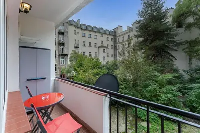 a balcony with a red table and chairs and a building at Sereno Vista Apartment by BookingHost in Kraków