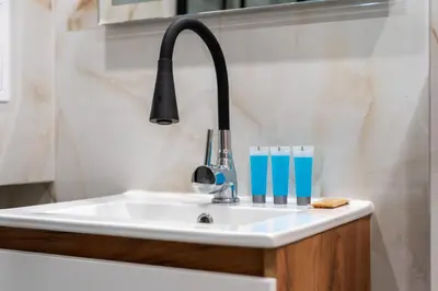 a kitchen sink with a black faucet and two glasses at Sereno Vista Apartment by BookingHost in Kraków