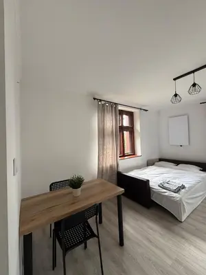 a bedroom with a bed and a table with a desk at Parkowa Apartment in Wadowice