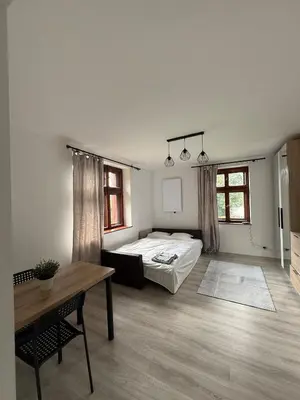 a bedroom with a bed and a table and windows at Parkowa Apartment in Wadowice