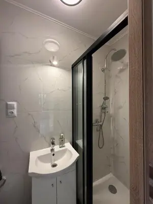 a white bathroom with a sink and a shower at Parkowa Apartment in Wadowice