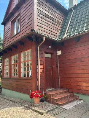 a wooden house with a door and some flowers at Parkowa Apartment in Wadowice