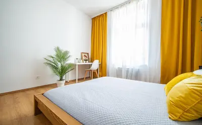 a bedroom with a large bed and a yellow curtain at Elegancki apartament - Kalwaryjska, centrum Krakowa in Kraków