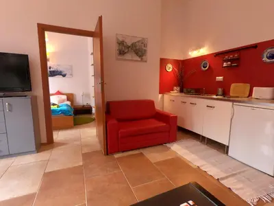 a living room with a red chair and a kitchen at Homely Apartment's Old Town in Kraków