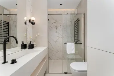 a white bathroom with a shower and a toilet at Cracow Novum Apartments by BookingHost in Kraków