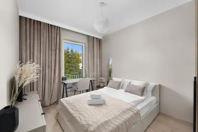 a white bedroom with a large bed and a table at Walerego Sławka Harmony Apartment by BookingHost in Kraków