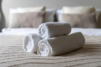a pile of towels stacked on a bed at Walerego Sławka Harmony Apartment by BookingHost in Kraków