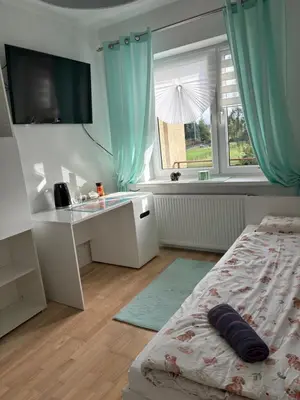 a bedroom with a bed and a desk and a window at Smile Room Balice in Liszki