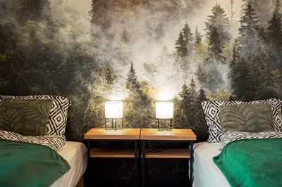 a bedroom with two beds and a forest mural at Domki Natura Zator in Graboszyce