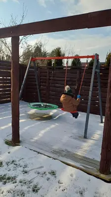 a person sitting on a swing in the snow at Domki Natura Zator in Graboszyce