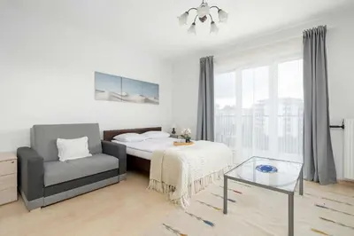 a bedroom with a bed and a chair and a glass table at Bright Studio in Cracow with Desk and Bathtub by Noclegi Renters in Kraków