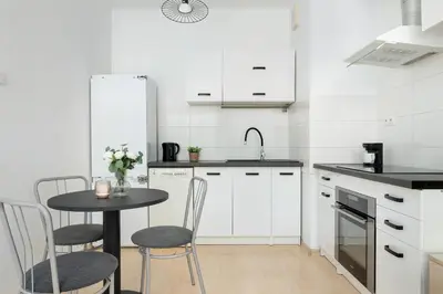 a kitchen with white cabinets and a table and chairs at Bright Studio in Cracow with Desk and Bathtub by Noclegi Renters in Kraków