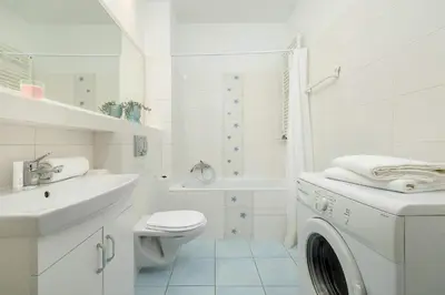 a white bathroom with a toilet and a sink at Bright Studio in Cracow with Desk and Bathtub by Noclegi Renters in Kraków