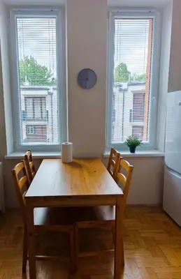 a wooden table and chairs in a kitchen with two windows at Krakow City Stay Vintage in Kraków