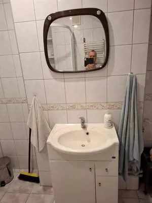 a man taking a picture of a bathroom with a sink at Pokoje u Zbigniewa