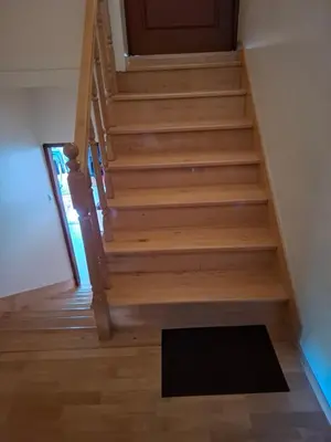 a wooden staircase with a door and a black rug at Pokoje u Zbigniewa