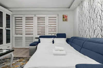 a living room with a bed and a blue couch at Nad Sudołem Homely Apartment by BookingHost in Kraków