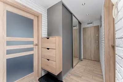 a walk in closet with a wooden cabinet and a mirror at Nad Sudołem Homely Apartment by BookingHost in Kraków