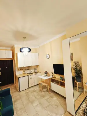 a kitchen with white cabinets and a table with a tv at Apartament Kataryniarza in Kraków