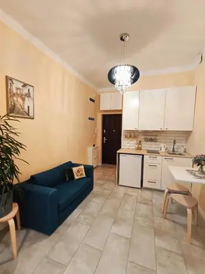 a living room with a blue couch and a kitchen at Apartament Kataryniarza in Kraków