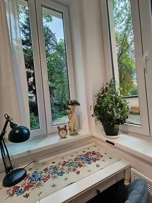 a table with flowers on it in a room with windows at Apartament Kataryniarza in Kraków