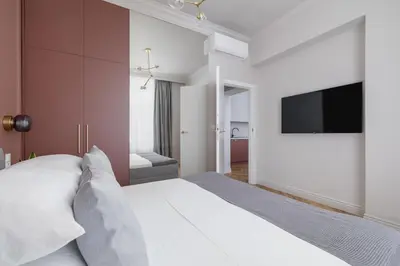 a bedroom with a white bed and a flat screen tv at 4 Bedroom Apartment with Private Sauna and Parking in Kraków