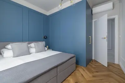 a bedroom with blue walls and a bed with white pillows at 4 Bedroom Apartment with Private Sauna and Parking in Kraków