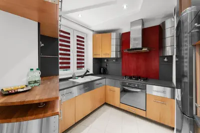 a kitchen with wooden cabinets and stainless steel appliances at Pod Fortem Homely Apartment by BookingHost in Kraków
