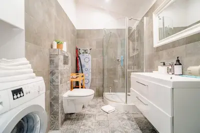 a bathroom with a toilet and a sink and a washing machine at Podgórze Studio - Air Con, Workdesk, Castle Nearby in Kraków