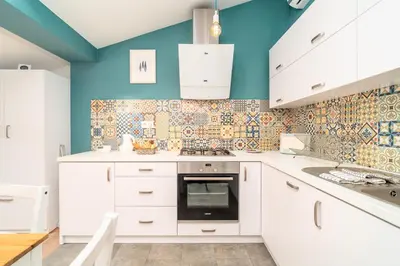 a kitchen with white cabinets and blue walls at Podgórze Studio - Air Con, Workdesk, Castle Nearby in Kraków