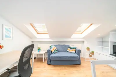 a living room with a blue chair and skylights at Podgórze Studio - Air Con, Workdesk, Castle Nearby in Kraków