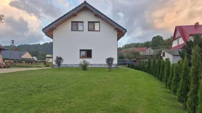 a white house with a green yard with trees at Relaks Nad Potokiem in Sidzina