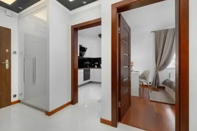 a hallway with a glass door leading to a kitchen at Modern Apartment with Desk and Balcony by Noclegi Renters in Kraków