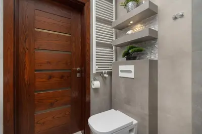 a bathroom with a toilet and a wooden door at Modern Apartment with Desk and Balcony by Noclegi Renters in Kraków