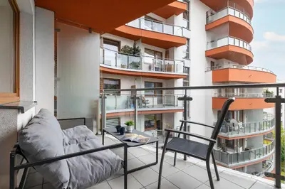 a balcony with a couch and a chair on a building at Modern Apartment with Desk and Balcony by Noclegi Renters in Kraków