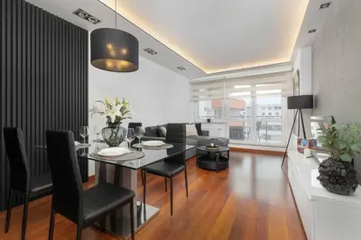 a living room with a dining room table with black chairs at Modern Apartment with Desk and Balcony by Noclegi Renters in Kraków