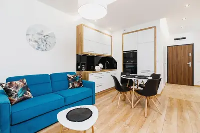 a living room with a blue couch and a table at Rakowicka Modern Apartment with Bathtub By Noclegi Renters in Kraków