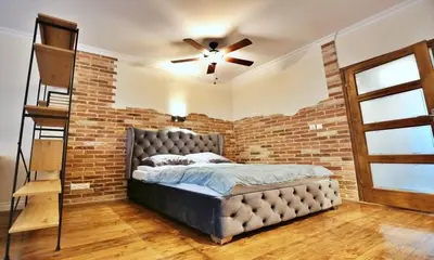 a brick walled bedroom with a bed and a ceiling fan at Old Town Apt Józefa Street 22 in Kraków